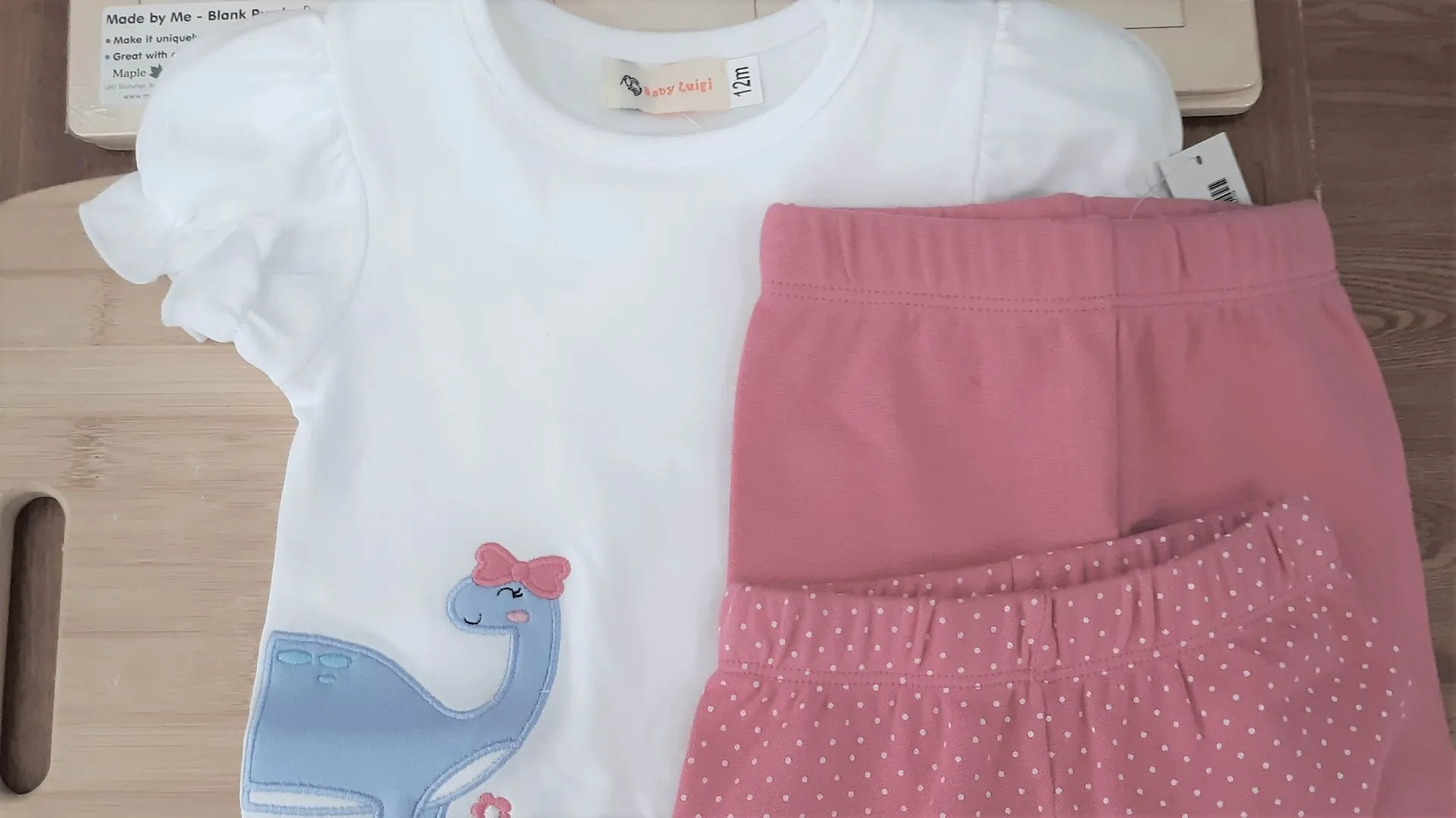 A baby girl 's t-shirt and shorts are sitting on a wooden table.