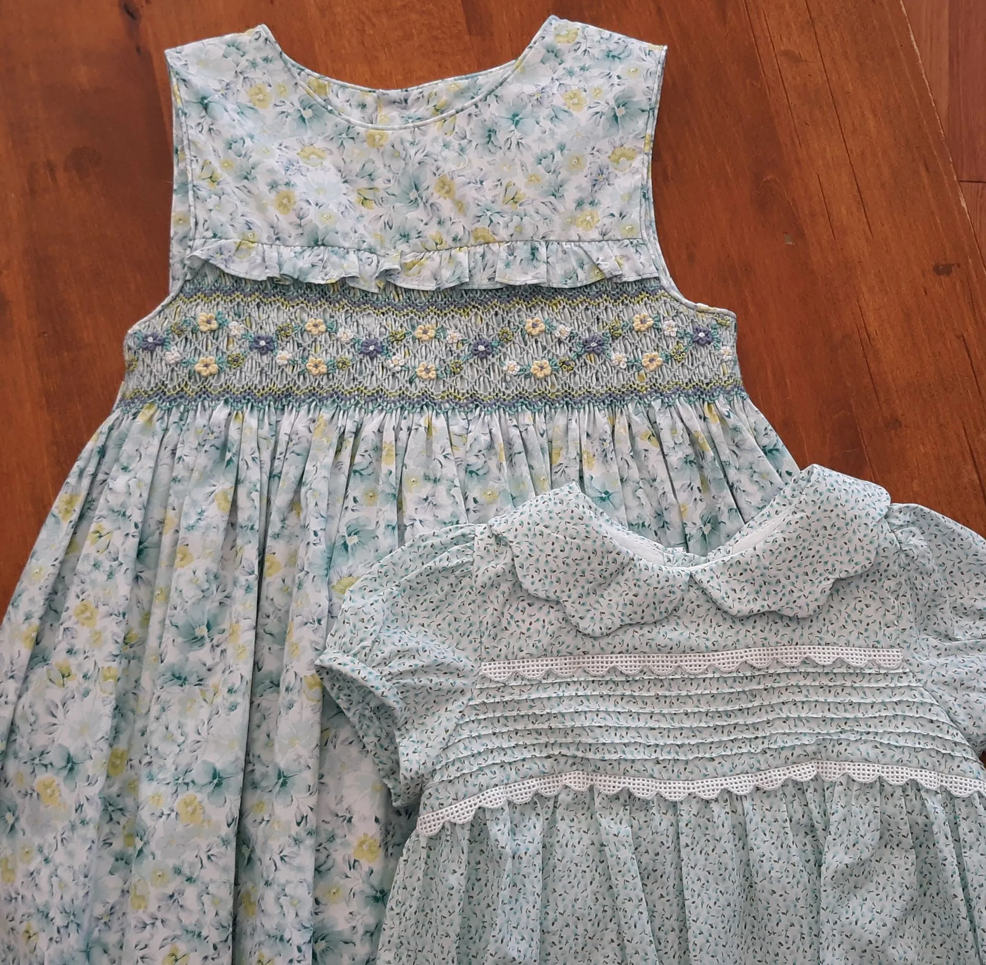 Two little girls dresses are on a wooden table