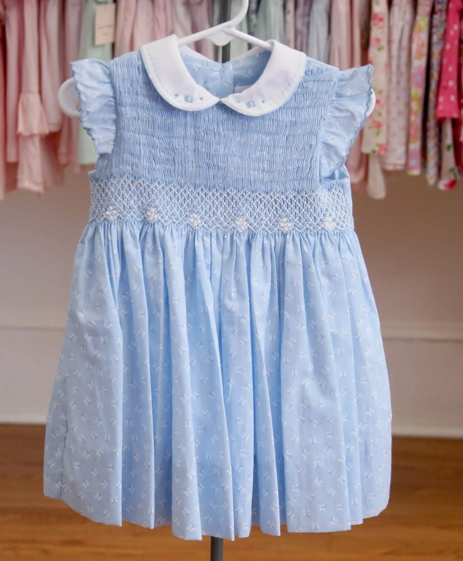 A light blue dress with a white collar is hanging on a hanger.