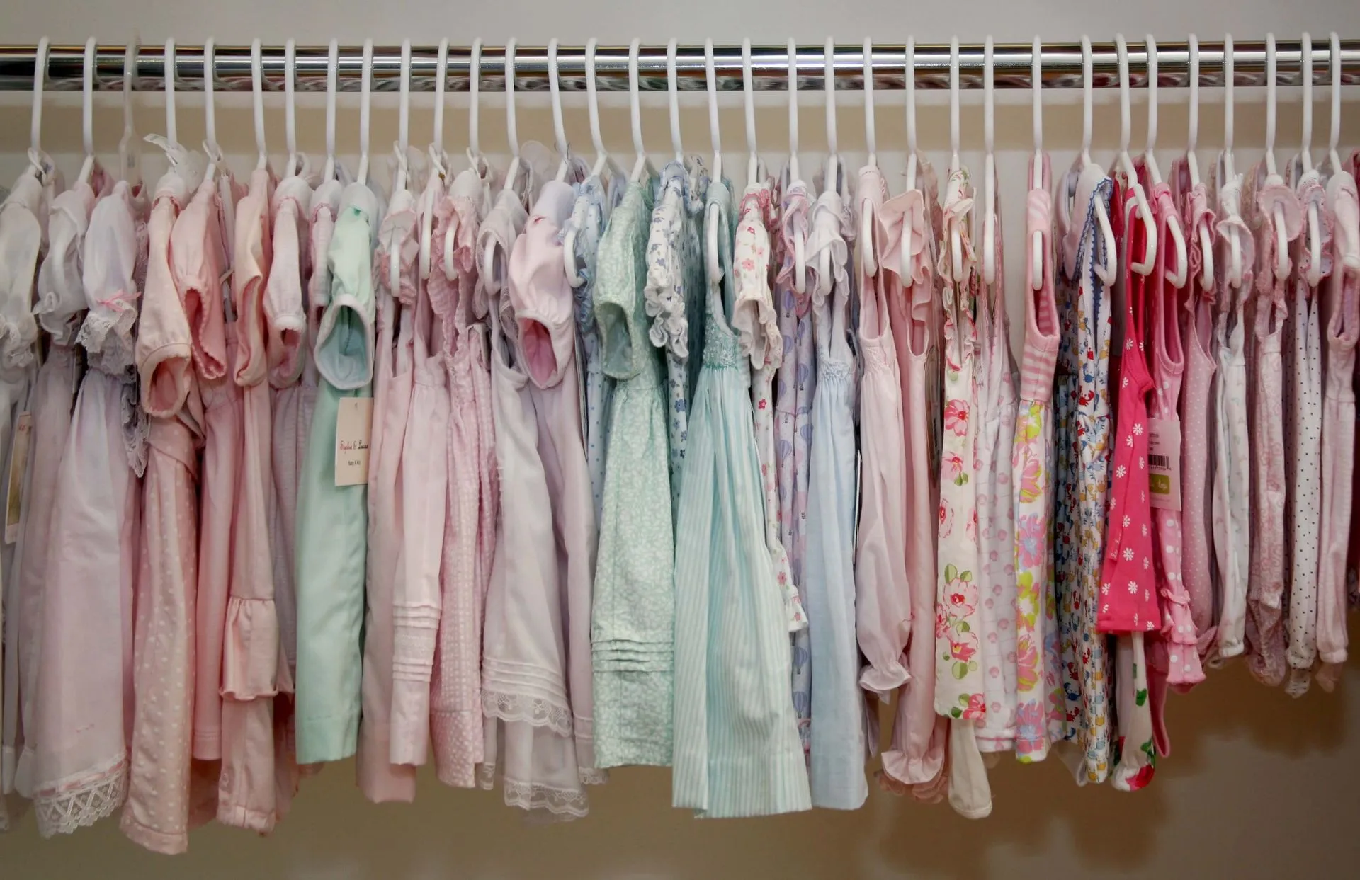 A closet filled with lots of baby clothes hanging on racks.