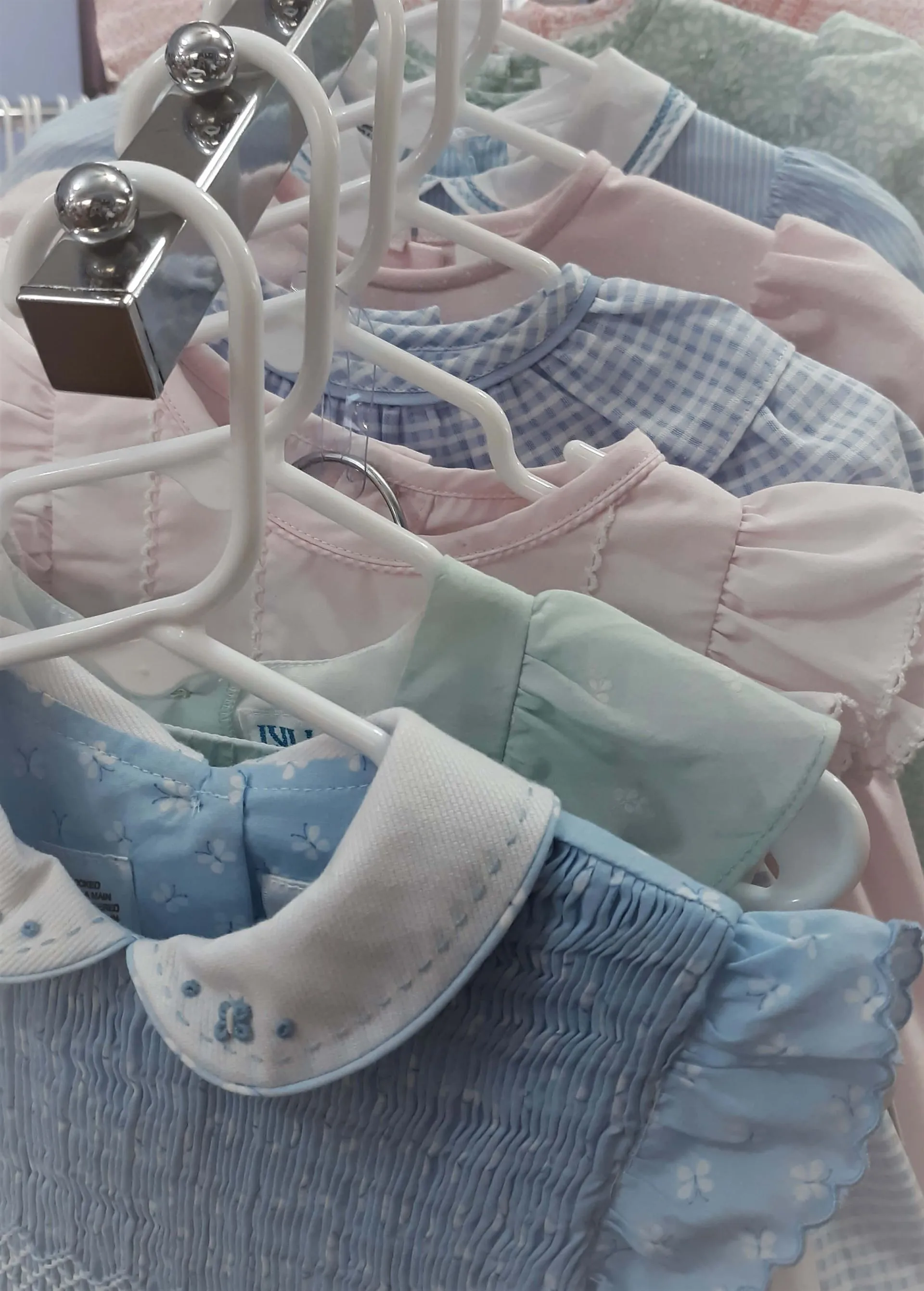 A row of baby clothes hanging on a rack