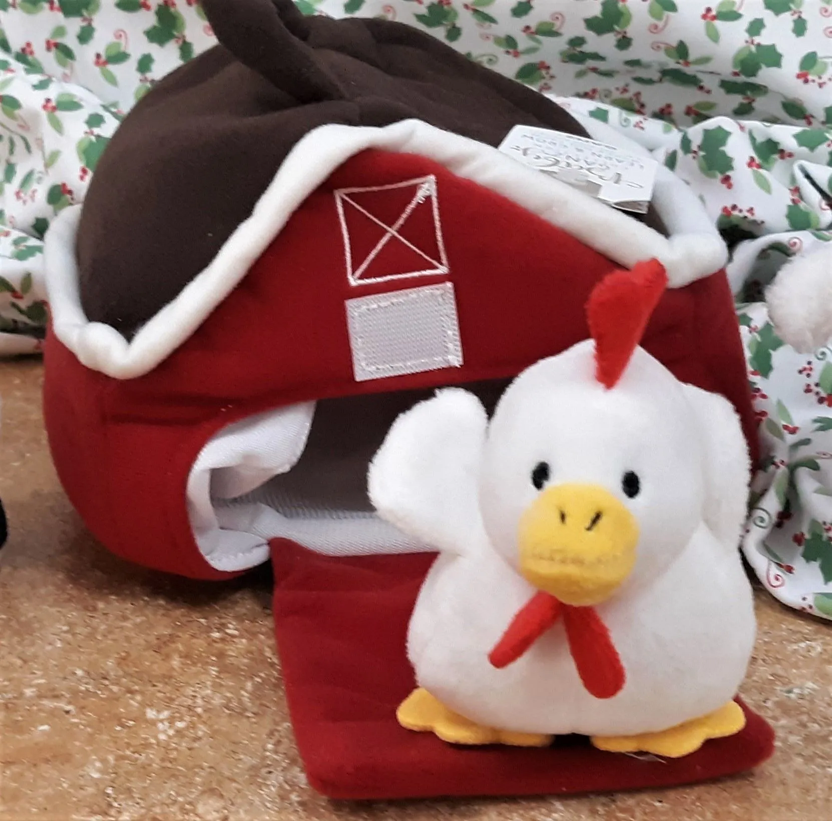 A stuffed chicken sits in front of a red barn