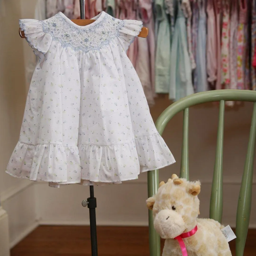 A white dress is hanging on a hanger next to a stuffed animal