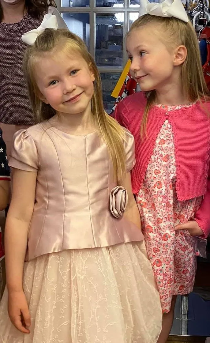 Two little girls are standing next to each other in a room.