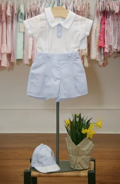 A baby 's outfit is displayed on a mannequin next to a potted plant